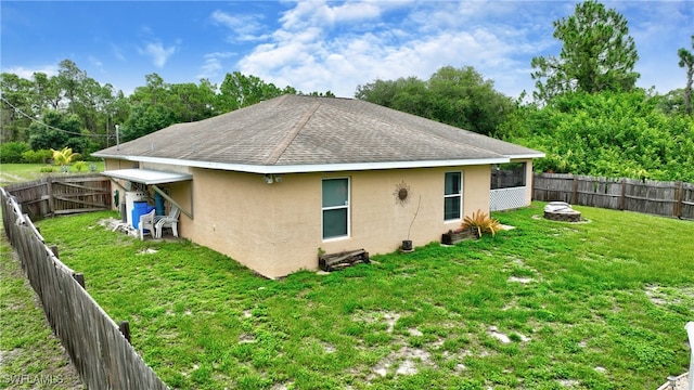 rear view of property featuring a yard and an outdoor fire pit