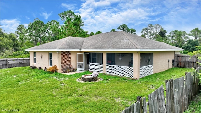 view of front facade featuring a sunroom, a front yard, and an outdoor fire pit