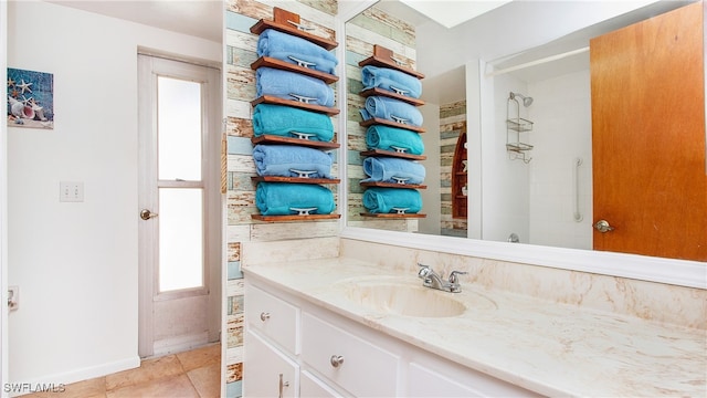 bathroom featuring tile patterned flooring, a tile shower, and vanity