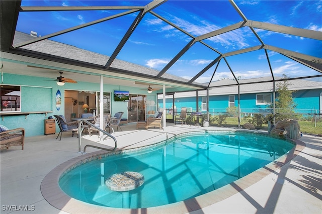 view of swimming pool featuring glass enclosure, ceiling fan, and a patio area