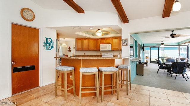 kitchen with a breakfast bar area, kitchen peninsula, beamed ceiling, and white appliances