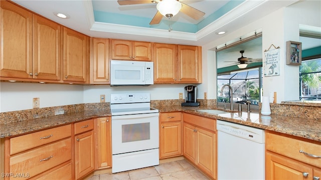 kitchen featuring stone countertops, white appliances, sink, and a tray ceiling