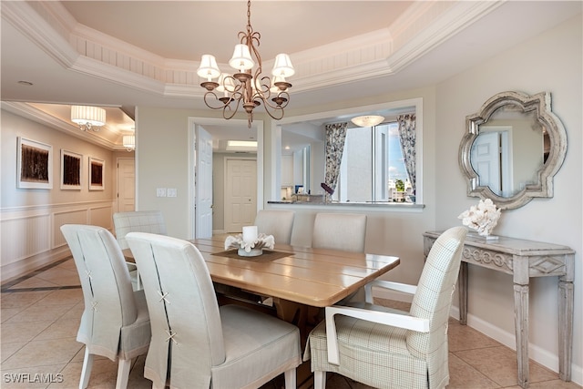 tiled dining room with a raised ceiling, crown molding, and a notable chandelier