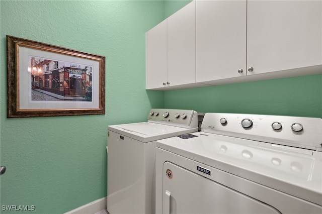 clothes washing area with cabinets and washing machine and dryer