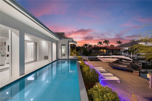 pool at dusk featuring a wooden deck