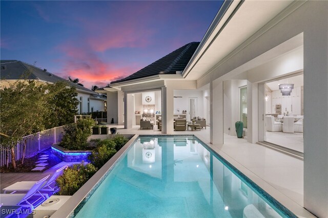 pool at dusk featuring outdoor lounge area and a patio