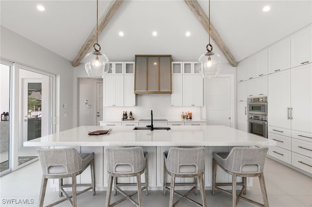 kitchen featuring a breakfast bar, stainless steel double oven, white cabinets, and a large island