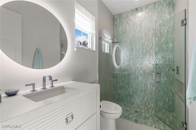 bathroom featuring vanity, a shower with shower door, and toilet