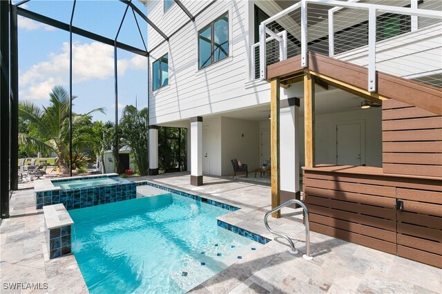 view of pool with a patio area, an in ground hot tub, and glass enclosure