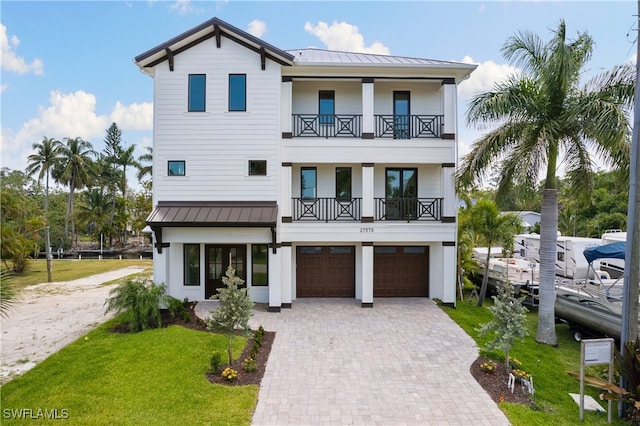 view of front of home featuring a front yard, a balcony, and a garage