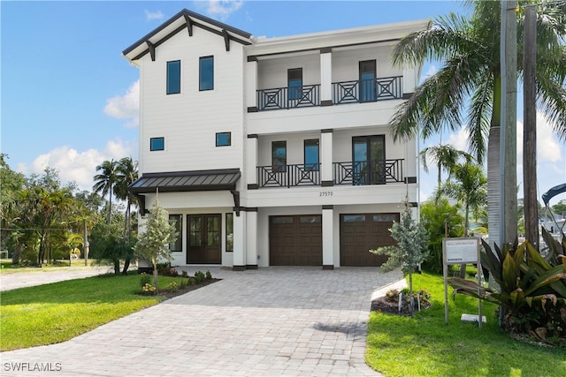 beach home with a front yard, a garage, and a balcony