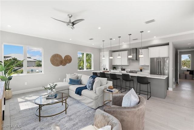 living room featuring light hardwood / wood-style floors, crown molding, plenty of natural light, and ceiling fan