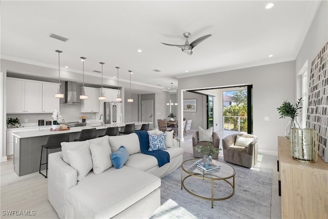 living room with sink, crown molding, light hardwood / wood-style floors, and ceiling fan