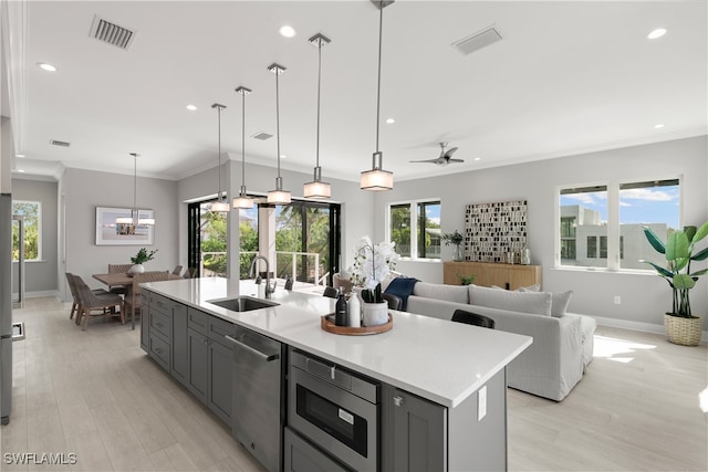 kitchen featuring gray cabinetry, sink, dishwasher, light hardwood / wood-style flooring, and a center island with sink