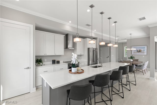 kitchen with a large island, stainless steel appliances, sink, wall chimney exhaust hood, and decorative light fixtures