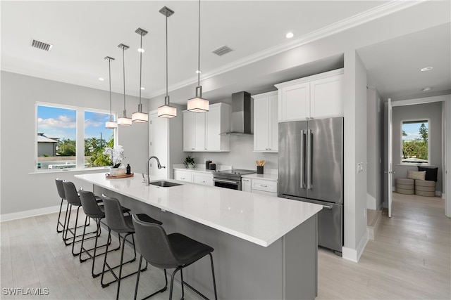 kitchen with a spacious island, sink, pendant lighting, wall chimney exhaust hood, and stainless steel appliances