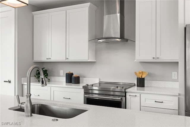 kitchen featuring wall chimney range hood, light stone countertops, sink, white cabinetry, and stainless steel electric range