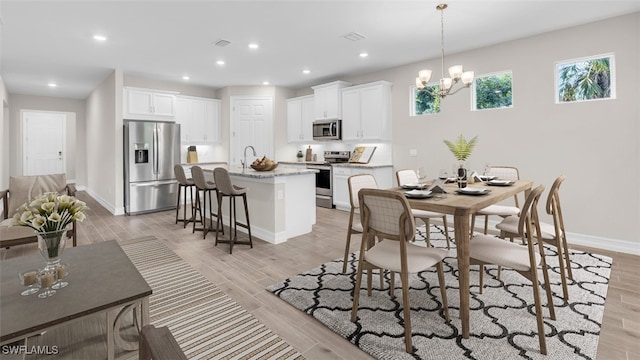 dining space featuring sink, a notable chandelier, and light wood-type flooring