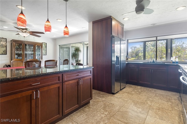 kitchen featuring dark stone countertops, a textured ceiling, sink, and stainless steel fridge