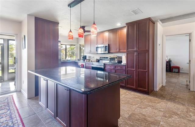 kitchen featuring stainless steel appliances, dark stone counters, a healthy amount of sunlight, and a kitchen island