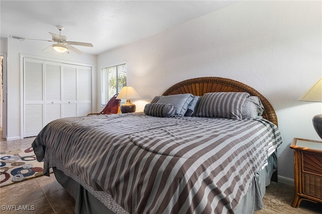 bedroom with dark tile patterned flooring, ceiling fan, and a closet