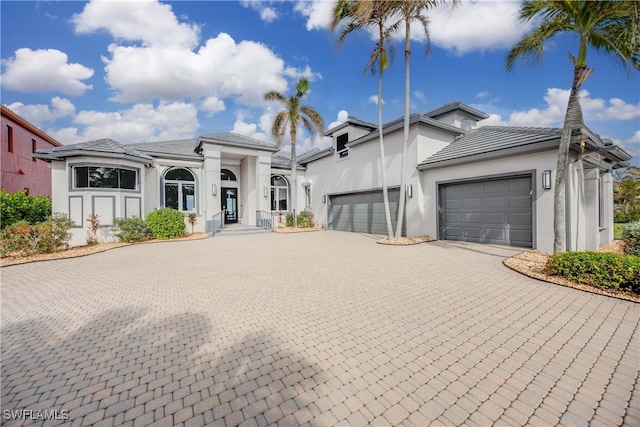 view of front of house featuring an attached garage, decorative driveway, and stucco siding