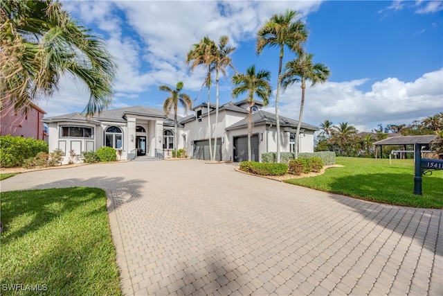 mediterranean / spanish-style house with decorative driveway, an attached garage, stucco siding, and a front yard