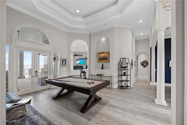 game room with french doors, a tray ceiling, decorative columns, and light wood-style floors