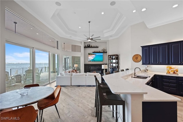 kitchen featuring a breakfast bar, a water view, open floor plan, a sink, and a peninsula