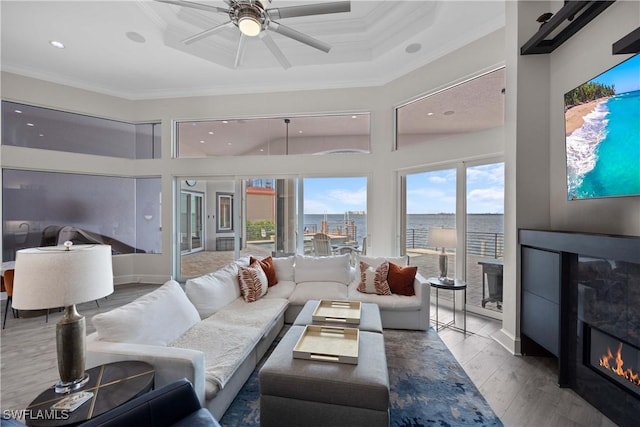 living area with a city view, a water view, wood finished floors, ornamental molding, and a glass covered fireplace