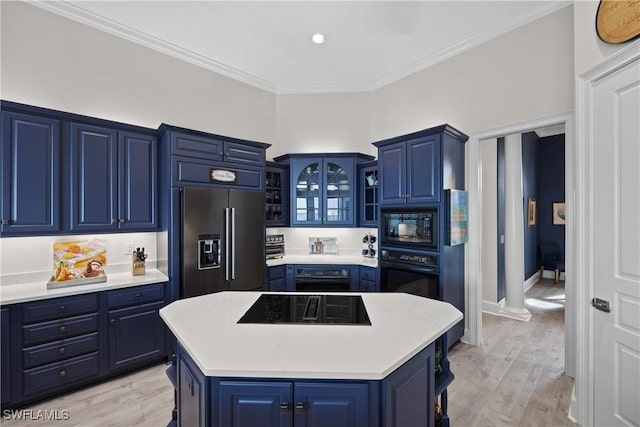 kitchen with glass insert cabinets, light countertops, a kitchen island, and black appliances