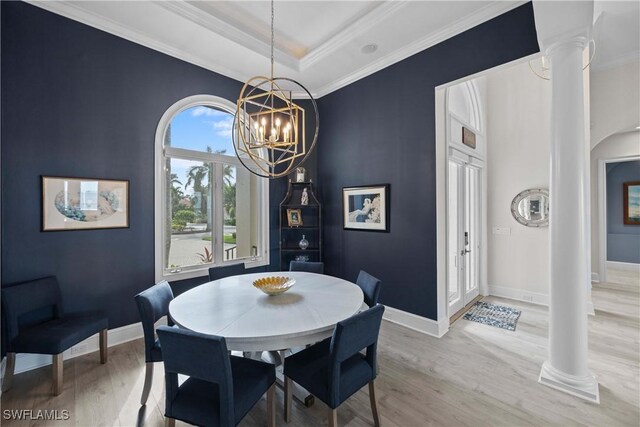 dining room with crown molding, ornate columns, and wood finished floors