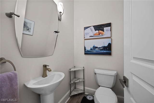 half bath with baseboards, a sink, and toilet