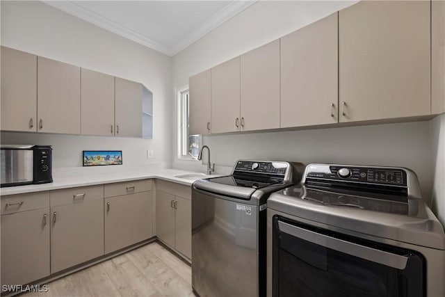 clothes washing area featuring light wood finished floors, cabinet space, ornamental molding, separate washer and dryer, and a sink