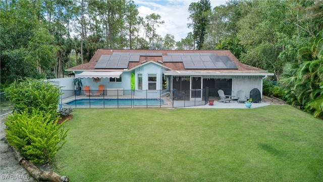 back of property featuring solar panels, a lawn, a patio, and a fenced in pool