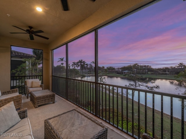 sunroom / solarium featuring ceiling fan and a water view