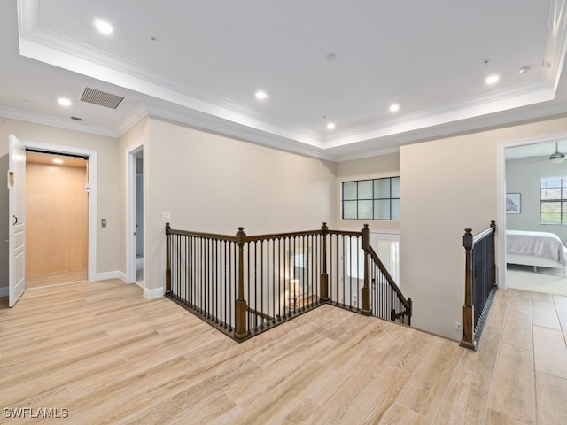 hall featuring a tray ceiling, crown molding, and light hardwood / wood-style flooring