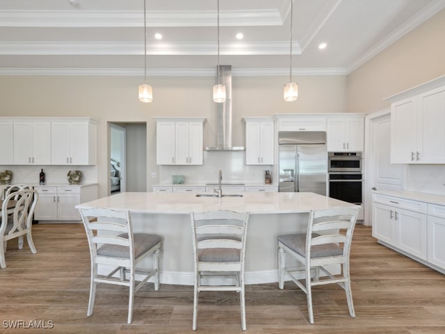 kitchen featuring appliances with stainless steel finishes, a kitchen island with sink, sink, decorative light fixtures, and white cabinets