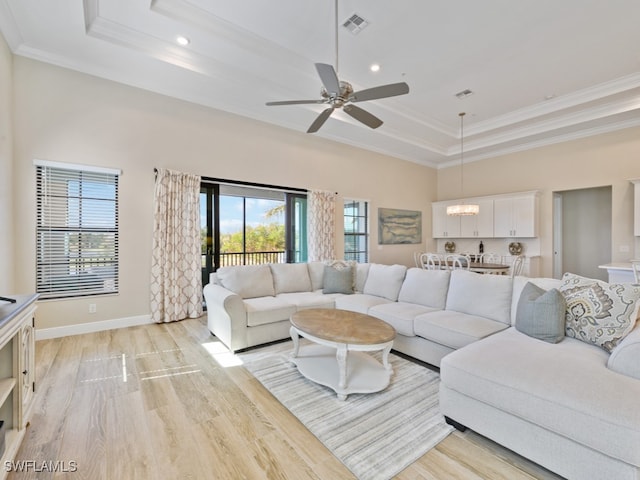 living room with a raised ceiling, crown molding, and plenty of natural light