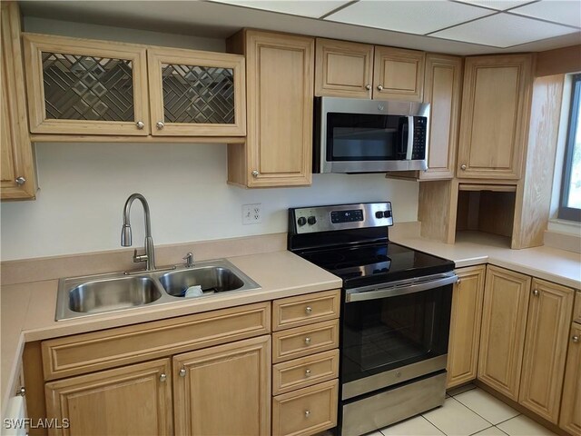 kitchen featuring a drop ceiling, sink, light tile patterned floors, and stainless steel appliances