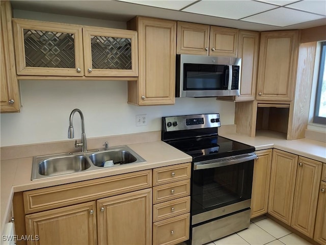 kitchen featuring light countertops, appliances with stainless steel finishes, glass insert cabinets, light tile patterned flooring, and a sink