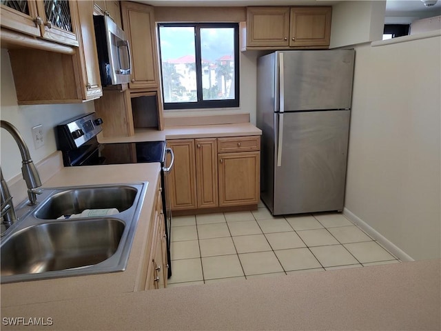 kitchen featuring light tile patterned floors, stainless steel appliances, a sink, baseboards, and light countertops