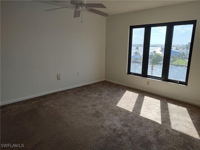 unfurnished room with carpet, a water view, and ceiling fan