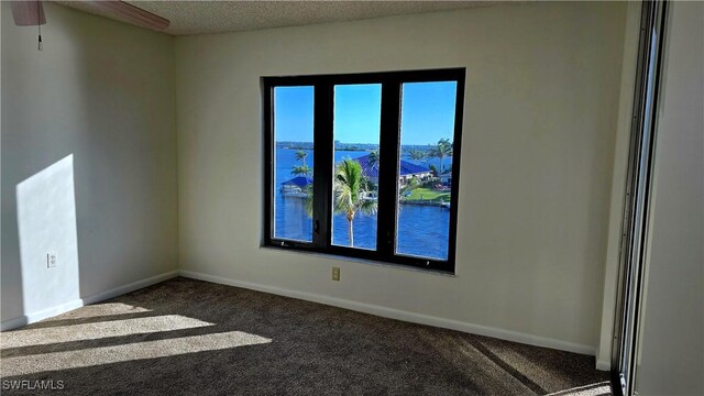 carpeted empty room featuring baseboards, a ceiling fan, and a textured ceiling