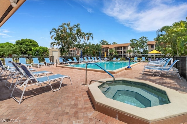 view of swimming pool featuring a hot tub and a patio area