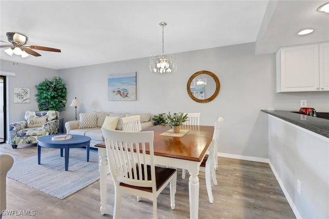 dining area with light hardwood / wood-style floors and ceiling fan with notable chandelier