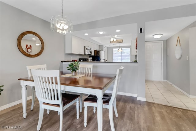 dining room with light wood-type flooring and ceiling fan with notable chandelier