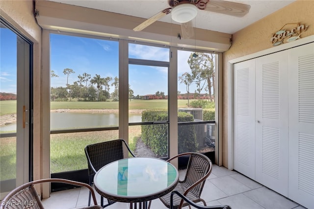 sunroom / solarium featuring ceiling fan and a water view