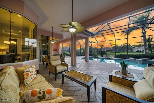 patio terrace at dusk with ceiling fan, glass enclosure, and an outdoor hangout area