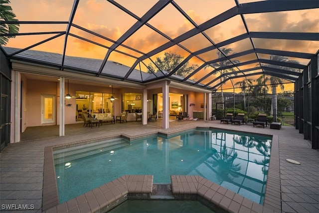 pool at dusk with a patio and glass enclosure